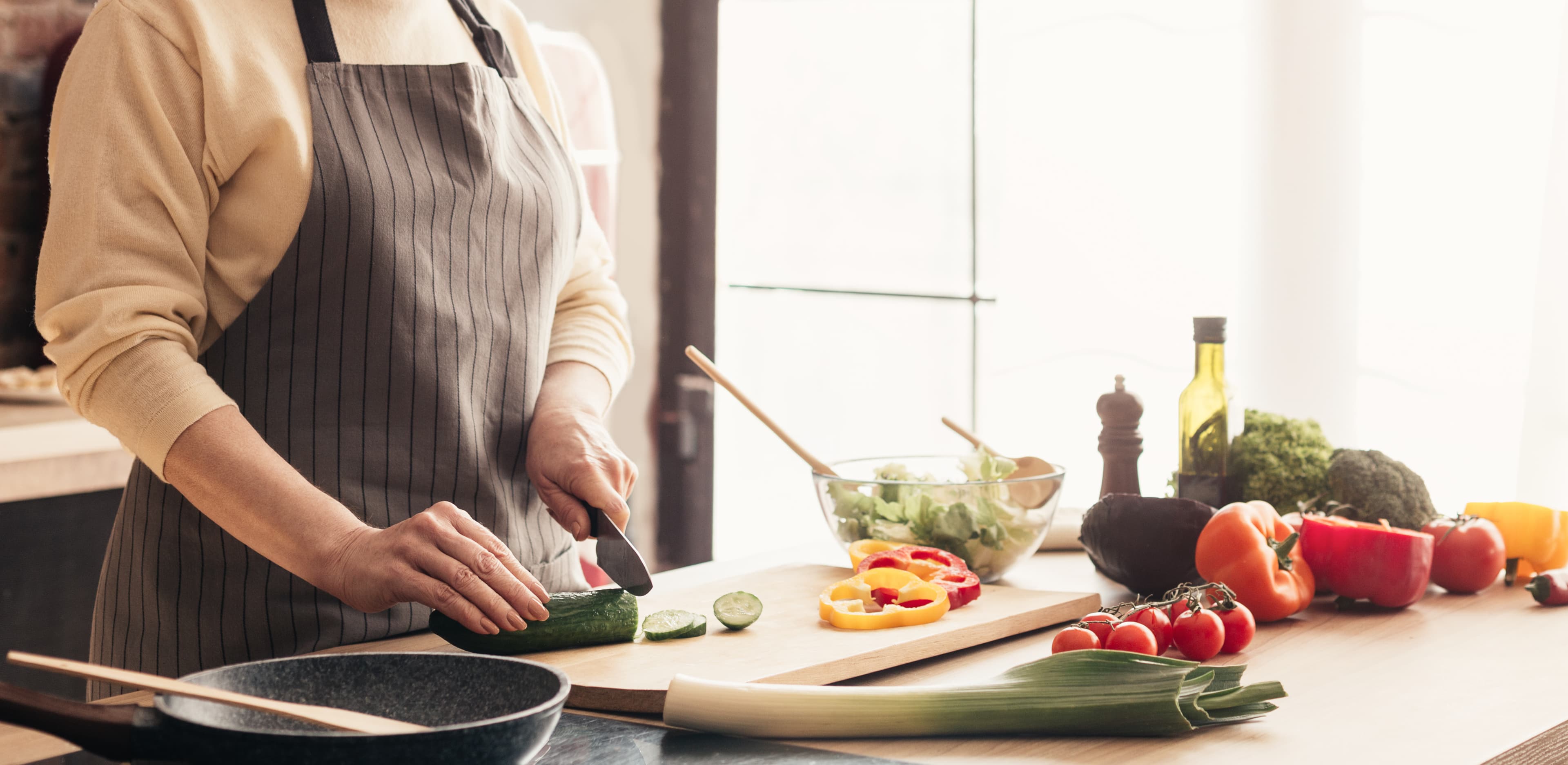 A cook slicing vegetables on a wooden board